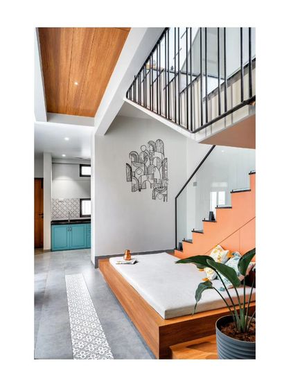 A cozy seating area is tucked under the stairs, making efficient use of space in this narrow home. The pop of orange on the stair wall adds a playful touch.
