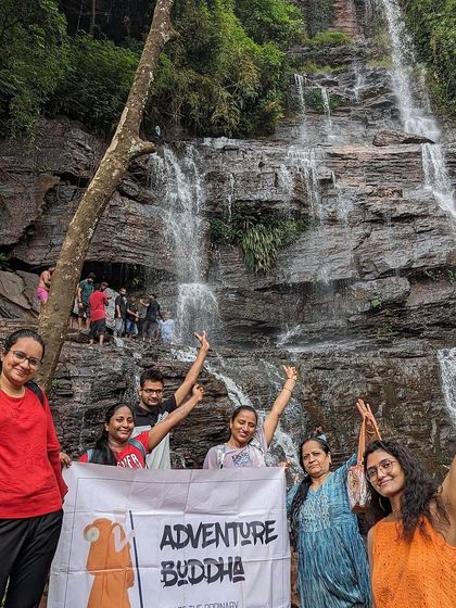 Our group celebrating with the Adventure Buddha banner in front of a beautiful waterfall in Chikmagalur. It’s a perfect spot for a memorable group photo.