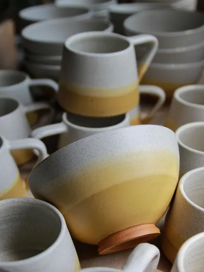 A close-up of the mustard and white ombre-glazed bowls and mugs. This matte glaze has a beautiful vibrancy and is one of my favorites to work with for custom tableware sets.