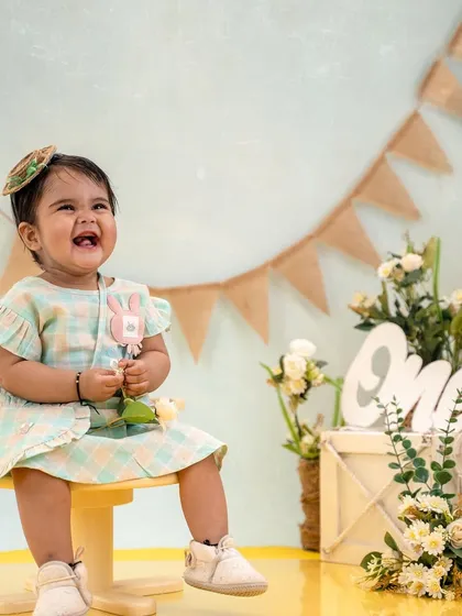 A burst of pure happiness. This little girl's laughter filled the studio during her first birthday photoshoot, set against a charming rustic backdrop.