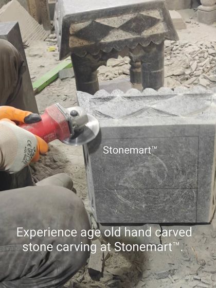 "Experience age-old hand-carved stone carving at Stonemart." This image captures the essence of our craft, as an artisan works on a granite temple for a home.