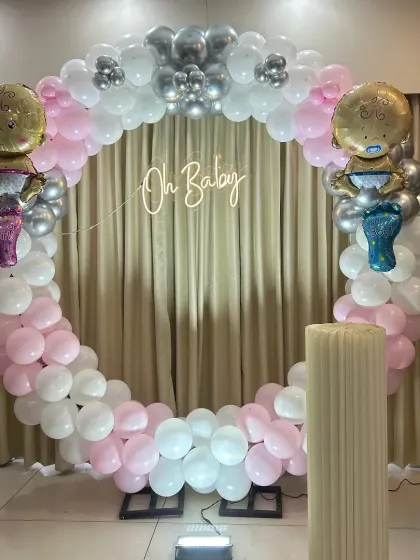 This modern and elegant "Oh Baby" ring is perfect for baby showers. The circular frame is adorned with a mix of pink, white, and silver chrome balloons, with a soft neon sign at the center, creating a beautiful focal point for celebrating the parents-to-be.