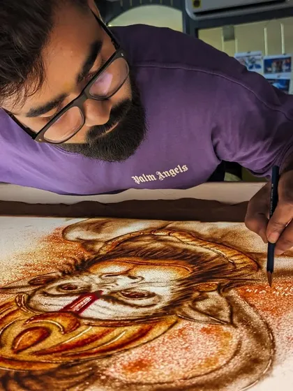Adding color and detail to my Hanuman ji sand art with a fine brush.