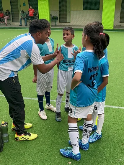 A coach giving tactical instructions to the Under-9 team during a break in play. Clear communication is vital.