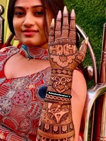 A happy client showing off her full-arm traditional mehandi, featuring elephants and intricate filler patterns.