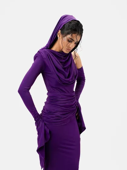 This shot shows the versatility of the wet-look updo, with the gown's hood pulled up. The hairstyle remains structured and visible, adding to the overall drama of the fashion look.