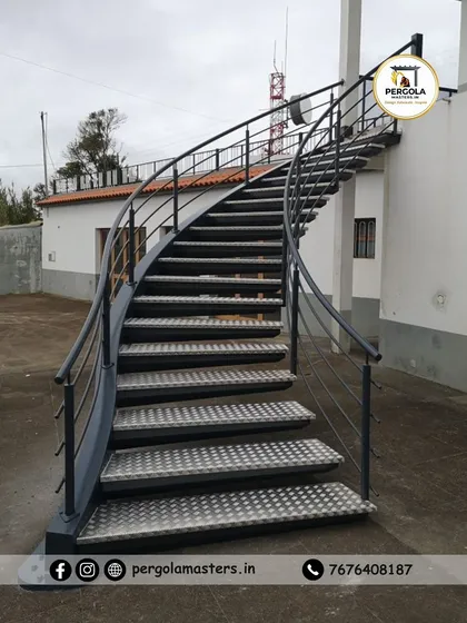 A practical and durable outdoor spiral staircase featuring anti-slip checkered plate treads. This design is ideal for providing access to rooftops or terraces in commercial or industrial settings where safety is paramount.