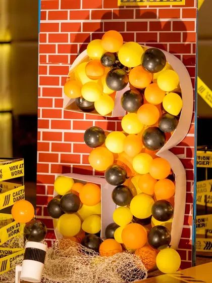 This large number '3' prop, designed to look like a deconstructed brick wall filled with balloons, served as a fantastic photo backdrop and a major focal point for the construction-themed birthday party.