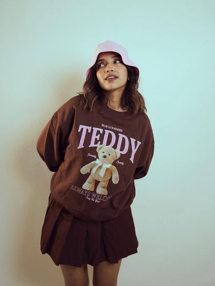 A thoughtful and cute pose from the studio shoot with Diksha Rawat. The simple background keeps the focus on her and the graphic sweatshirt.
