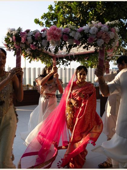 The bride's grand entrance under a beautiful floral phoolon ki chaadar. This shot captures the significance of the moment and the bride's graceful walk towards her new life.
