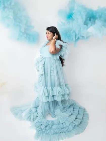 A dreamy portrait with the mom-to-be surrounded by fluffy blue clouds. This creative shot in a beautiful ruffled gown adds a touch of fantasy to the maternity session.