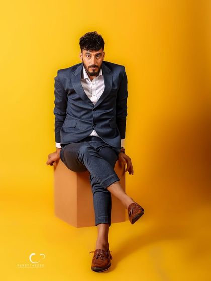 A sharp and stylish male portrait against a vibrant yellow background. The classic suit paired with a confident, direct gaze creates a modern and compelling image.