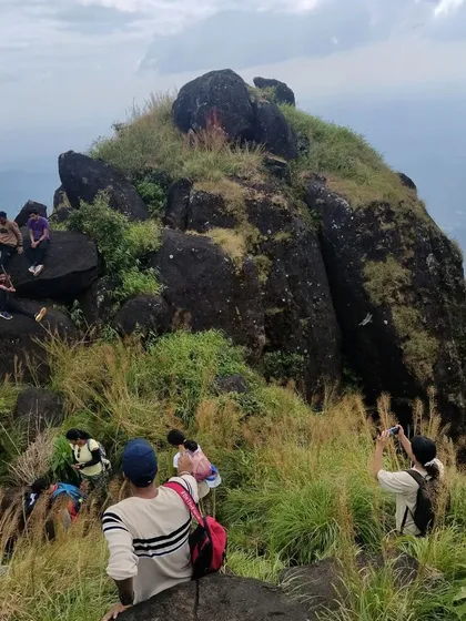 Trekkers exploring the rocky summit of Kurinjal.