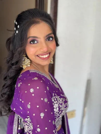 A bright, smiling portrait of the client, looking ready for a wedding party.