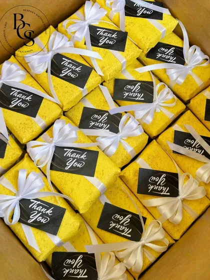 A carton filled with brightly wrapped thank you gifts. The vibrant yellow paper and contrasting white ribbons make for a cheerful and memorable way to show appreciation.