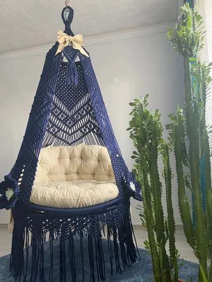 This single seater sofa swing in dark blue is decorated with macrame flowers and a bow for a custom look. It shows how we can add small details to make your swing unique.