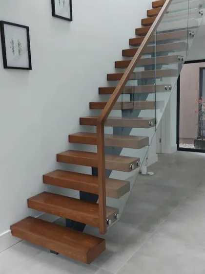 Another angle of the finished centre-spine staircase, showing how the toughened glass balustrade is fixed directly to the oak treads for a seamless look.