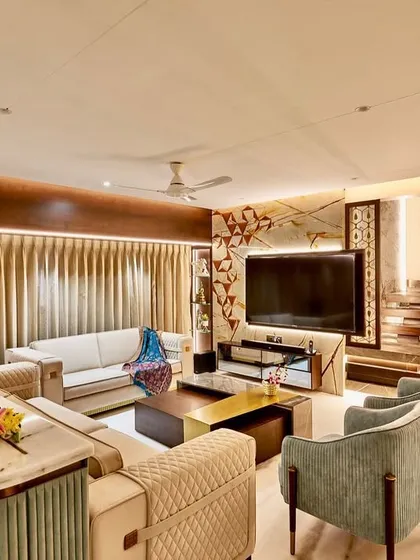 This living room combines traditional warmth with modern luxury. The design features a custom media wall, a staircase with integrated lighting, and a mix of quilted and smooth upholstery for textural variety.