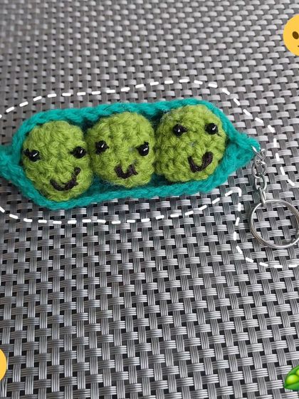 A close-up of the happy little peas in a pod keychain. Their smiling faces are sure to brighten your day.