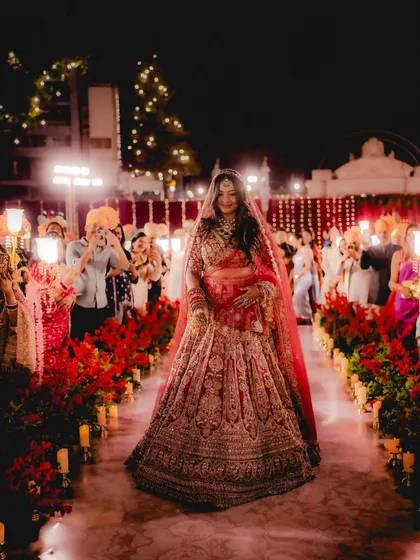 The bride's grand entrance down an aisle of glowing candles and red flowers. We capture the anticipation and awe of this pivotal moment.