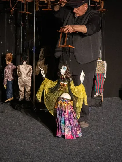 A behind-the-scenes look at the puppeteer from 'Il Fil'armonico' with his collection of marionettes, each waiting for their moment in the spotlight.