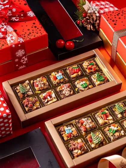 Boxes of my Christmas-themed date squares, decorated with tiny edible trees, presents, and reindeer. This is a healthier but equally festive treat, perfect for gifting.
