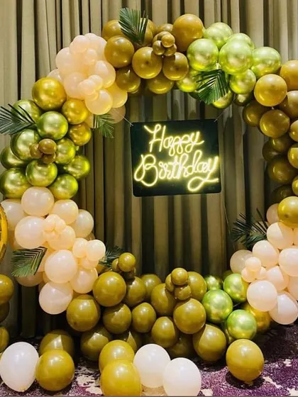 An elegant balloon ring in olive green, peach, and white, with a neon sign and a large number '9' foil balloon for a 9th or 90th birthday.