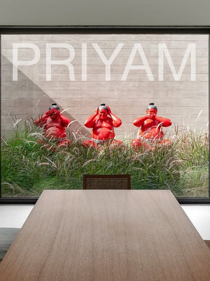 Three bright red sumo wrestler sculptures sit playfully among ornamental grasses. This installation, viewed from a dining room window, adds a bold pop of color and character to the minimalist landscape.