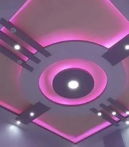 A square bedroom ceiling with a circular cutout, both highlighted with pink cove lighting. The dark accents add a touch of sophistication.