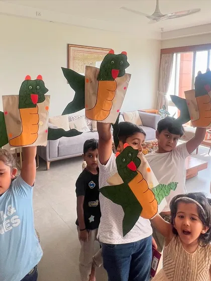 A group of kids proudly holding up their finished dragon puppets. This is the perfect takeaway from a fun-filled party, a reminder of the story and the fun they had.