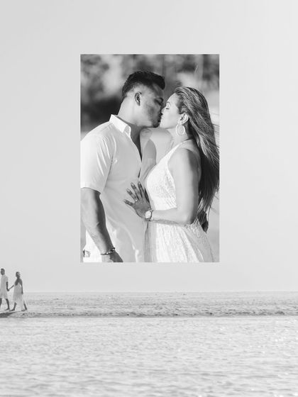 A creative black and white composition. A close-up of their kiss is layered over a wide shot of them walking on the beach, telling a story of both intimacy and journey.