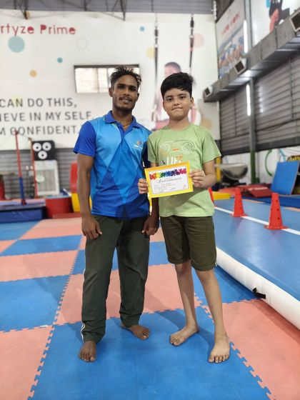 This student stands proudly with his coach and his new certificate, a symbol of his progress and hard work at Sportyze.