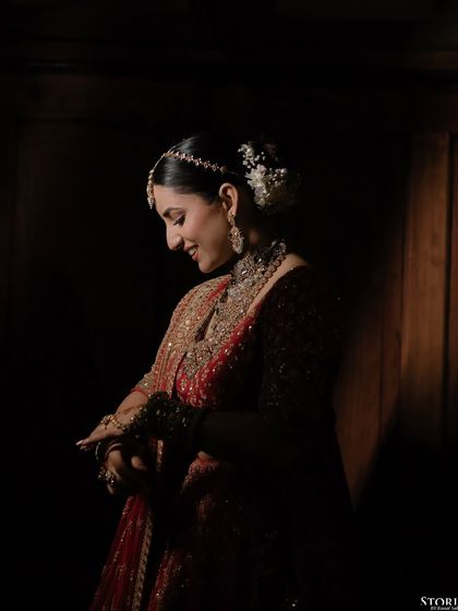 A beautifully lit, intimate portrait of the bride, Kajal, as she adjusts her jewelry, a quiet moment of preparation.