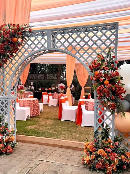 An elegant entrance arch for a baby shower, decorated with fresh flowers and balloons in shades of orange and grey. This archway welcomed guests into the garden party and set the tone for the event.