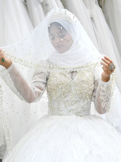 A close-up of a bride in her custom pearl-encrusted gown. The veil is also trimmed with pearls, creating a cohesive and incredibly luxurious look.