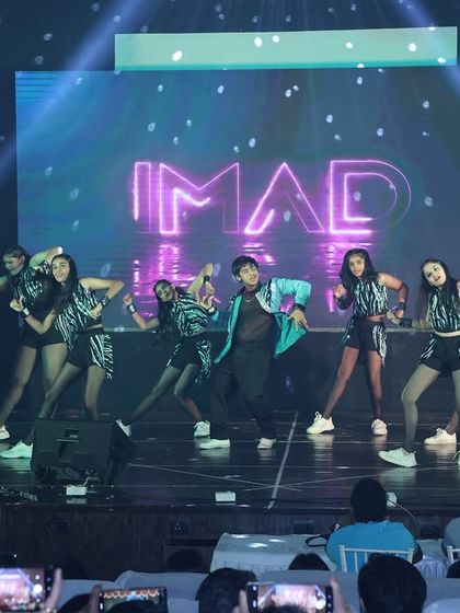 The stage lights catch our Bollyhop dancers in a high-energy pose, showing the professional production quality of our annual show.