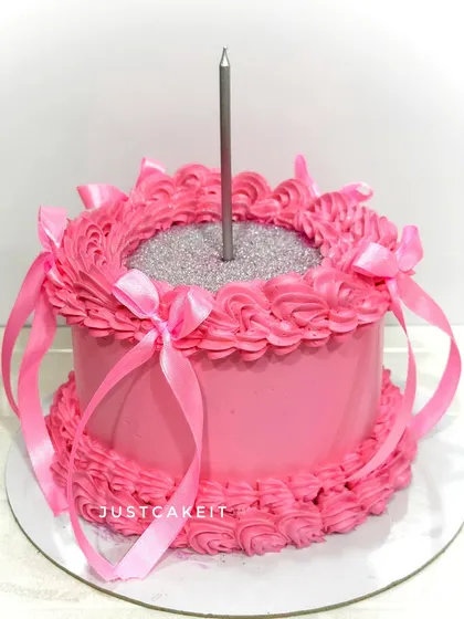 A simple yet striking pink cake with a glittery center. The piped border and satin ribbons give it a gift-wrapped appearance.