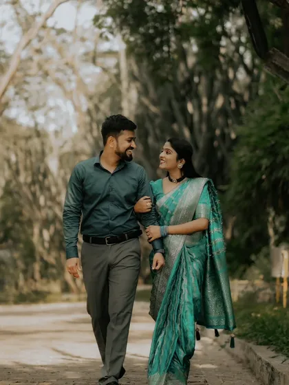 A walk to remember. This couple, dressed in elegant traditional attire, shares a loving look while strolling through a beautiful, tree-lined path.