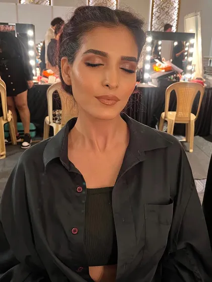 A candid moment backstage, showing the soft, neutral tones of the makeup before the final touches.