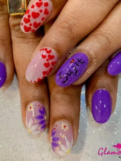 A personalized set that's full of love. We combined solid purple nails with accent nails featuring a client's name, a cascade of tiny hearts, and delicate, hand-painted flowers.