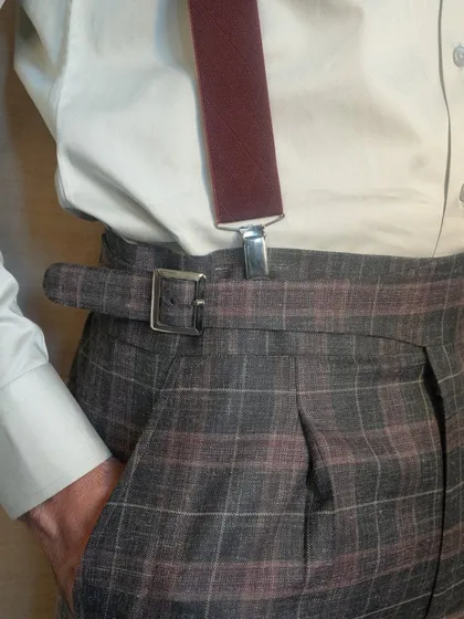 The intricate plaid pattern exudes a touch of vintage charm, while the sleek suspenders add a modern twist to the overall look.