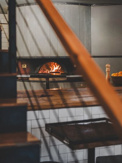 A glimpse of our wood-fired oven from the stairs. It's the heart of our kitchen and the source of all our delicious pizzas.