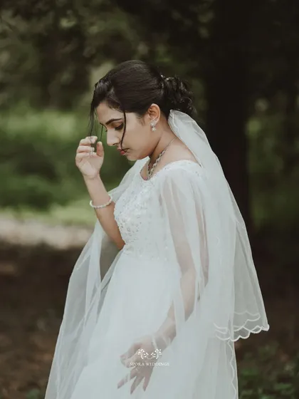 A pensive and beautiful portrait of the bride in a natural, wooded area, her veil gently draped.