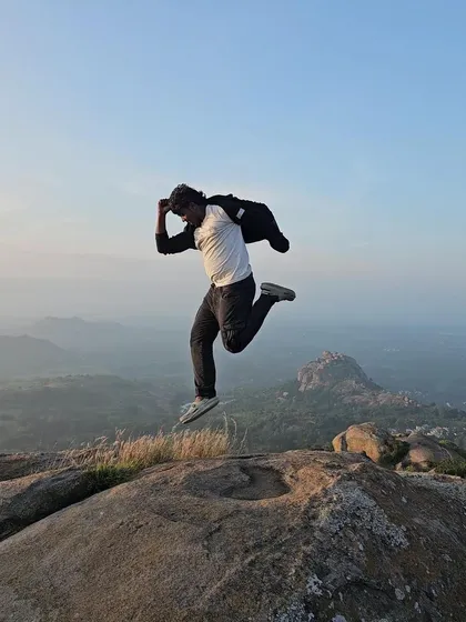 A trekker leaps in the air at the summit of Uttari Betta, full of energy from the beautiful morning.
