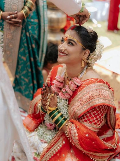 A sacred moment during the wedding ceremony. The bride's makeup is kept fresh and natural, with a traditional bindi and a radiant smile that lights up her face.