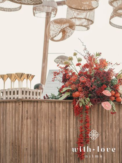 The bar at the beach event, decorated with tropical flowers and rattan lampshades.