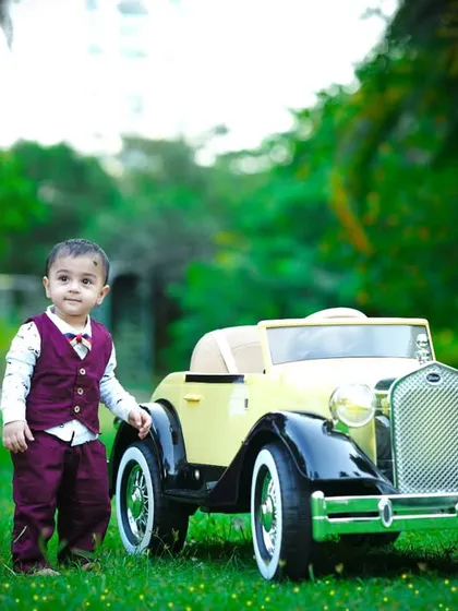 Standing next to his cool ride, this one-year-old is ready for his next adventure.
