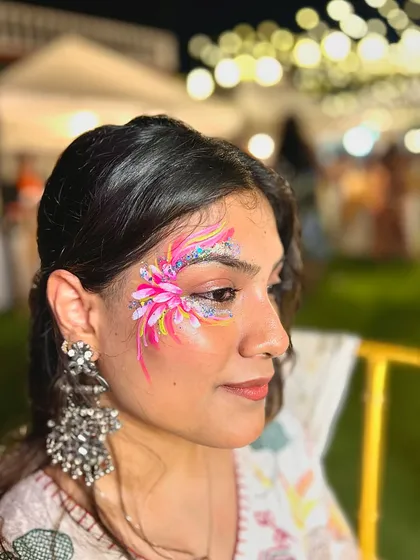 This vibrant pink floral piece is a great example of using bright colors and glitter to create a festive look. Notice how the design flows along the side of the eye, enhancing the client's features.
