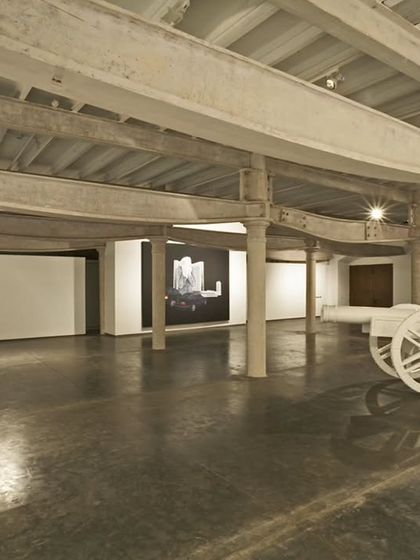 The vast, open interior of Project 88 gallery, a former industrial warehouse. We preserved the original cast-iron columns and steel beams, painting them white to unify the space and create a raw, textured backdrop for large-scale art.