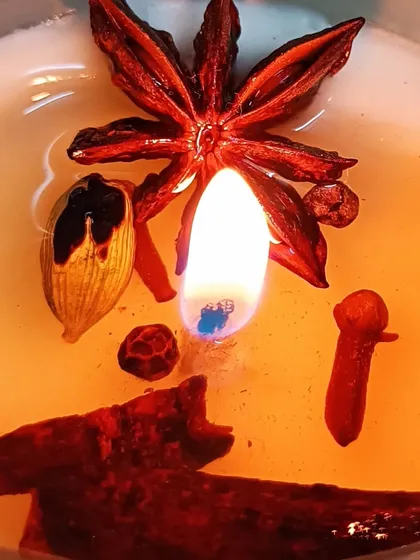 A close-up of a lit aromatherapy candle, showing the excellent fragrance release, or 'hot throw'. This one features a warm blend of whole spices like star anise, cinnamon, and cloves, creating a rich and comforting scent.